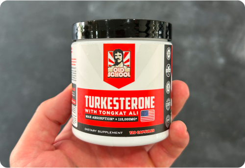 Hand holding a container of Old School Turkesterone dietary supplement.