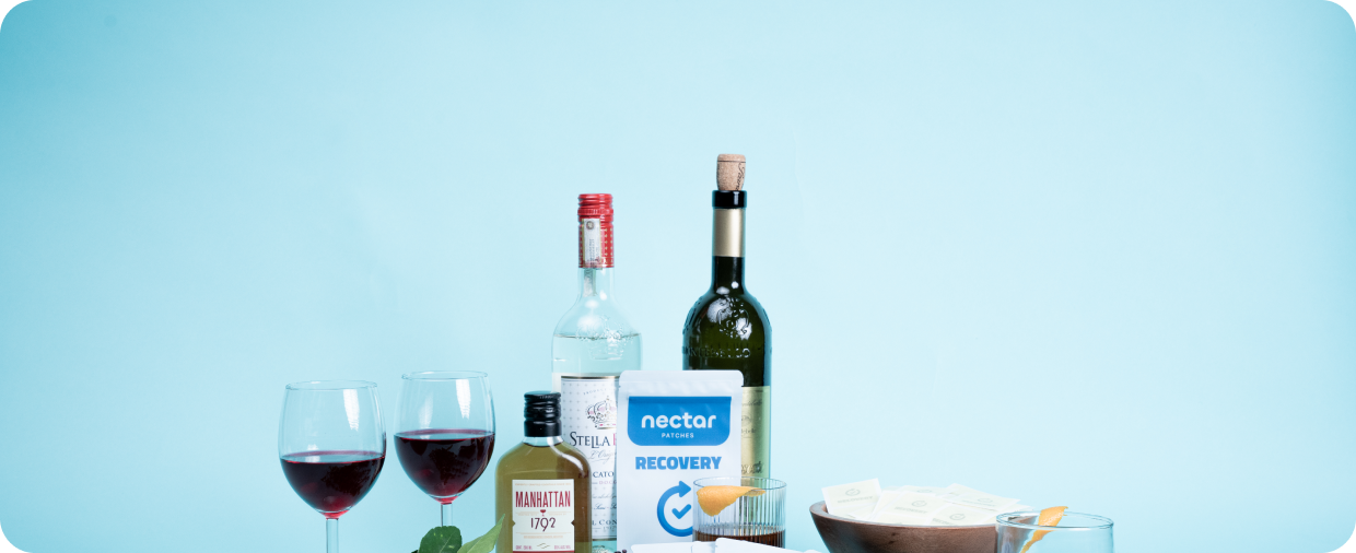 Assorted liquor bottles, two wine glasses, recovery patches, and orange slices on a blue background.