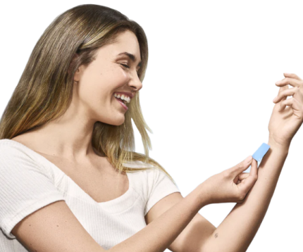 Smiling woman applying a blue patch to her arm.