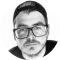 A person wearing glasses and a backward cap, looking directly at the camera.