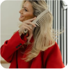 Woman combing her blonde hair while wearing a red coat.