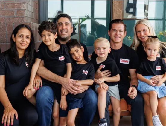 A group of adults and children wearing matching black shirts, sitting together and smiling.