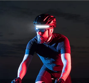 Cyclist wearing a helmet with front light in low-light conditions.