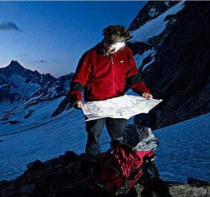 A person in a red jacket reads a map in a snowy mountain landscape.