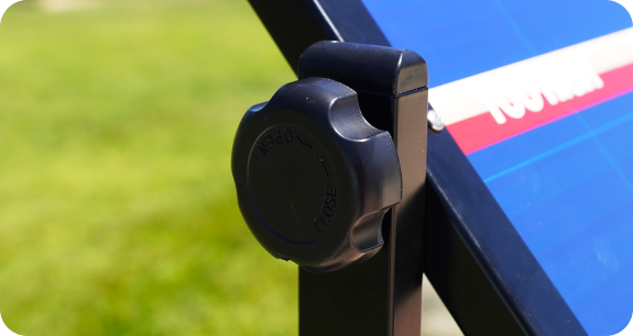 Close-up of a black plastic knob on a sunny outdoor structure.