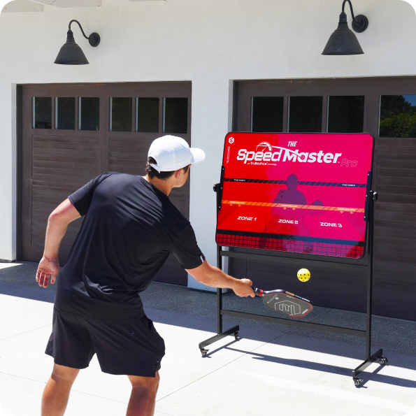 Person practicing pickleball with a SpeedMaster Pro training device outdoors.