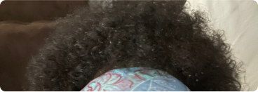 Curly hair with a blue and red patterned headband.