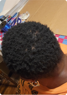Top view of a person with short curly hair, surrounded by cardboard and craft supplies.