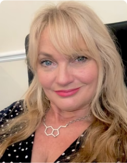 Portrait of a smiling woman with long blonde hair and a black polka dot shirt.