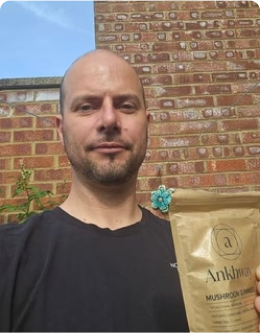 Man holding a package of Ankhara mushroom gummies outdoors.