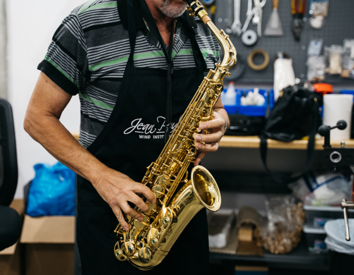 Person playing a saxophone in a workshop setting.