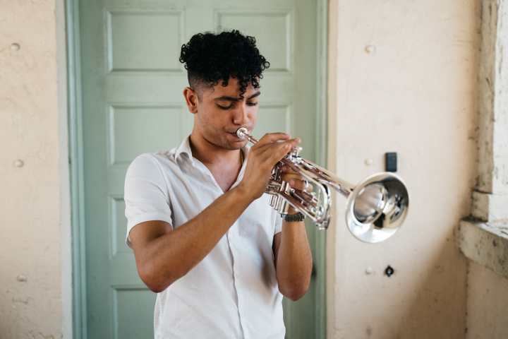 Person playing trumpet in front of a green door.