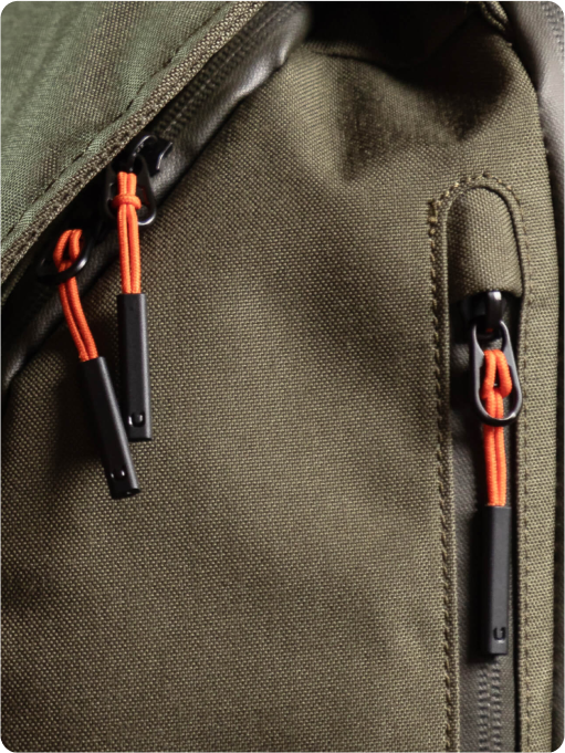 Close-up of green backpack with orange zipper pulls.