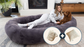 Woman relaxing in a large dog bed with a dog beside her.
