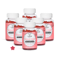 Six bottles of Good Hair vitamins with one star-shaped gummy beside them.