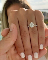 Close-up of a hand wearing an engagement ring with a sparkling diamond.