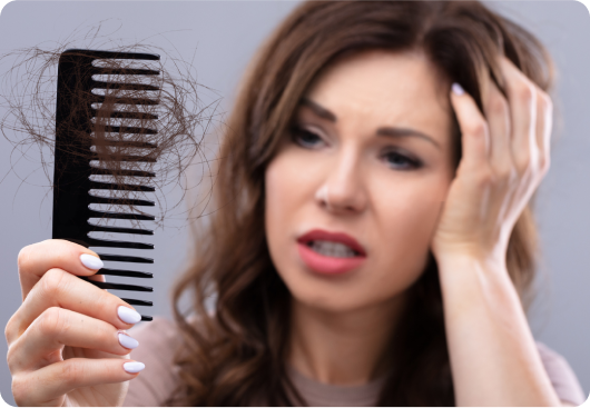 Woman looking distressed at hair tangled in a comb.