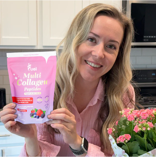 Woman holding a bag of multi collagen peptides next to pink flowers in a kitchen.