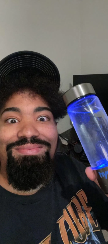 Man holding a glowing blue water bottle, smiling.