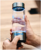 Person holding a modern glass bottle with blue LED lights.