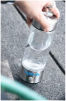 Person holding a portable clear blender bottle with metal accents on a gray surface.