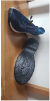 Blue sneakers on a wooden surface showing worn soles.