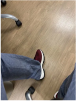 Person wearing jeans and red sneakers on a wooden floor.