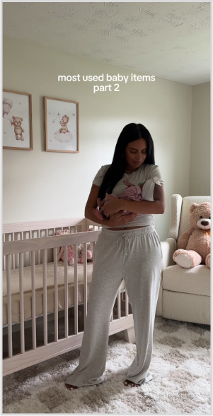 Woman holding baby in a nursery with crib and teddy bear.