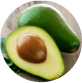 A whole and halved avocado on a wooden surface.