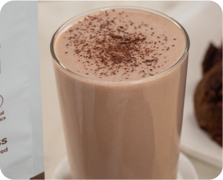 Glass of chocolate milkshake with cocoa powder on top.