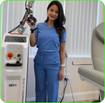 Person in blue scrubs standing next to medical equipment in an office.