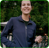 Person smiling outdoors, wearing a navy jacket and holding a jump rope.
