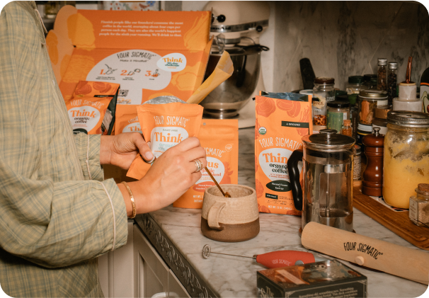 Person preparing a beverage with a Four Sigmatic product in a kitchen setting.