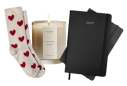 Cozy socks, a lit candle, and notebooks arranged together.