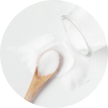 Wooden spoon of white powder next to a spilled glass jar.
