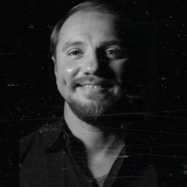 Smiling man in a black and white portrait with a textured background.