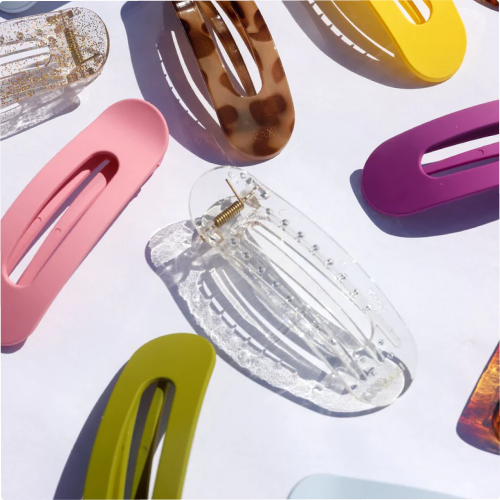 Colorful hair clips arranged on a white surface in sunlight.