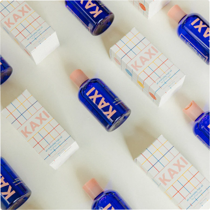 Blue bottles and boxes labeled 'KAXI' arranged on a white background.