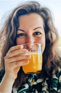 A woman smiling while holding a glass of orange juice.