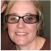 A smiling person with short blonde hair and glasses.