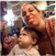 A woman playfully sticks out her tongue while holding a young child.