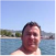 A man in the water with mountains in the background on a clear day.