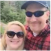 A smiling couple taking a selfie outdoors in nature.