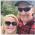 A man and woman smiling outdoors, wearing sunglasses.