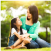 A mother and daughter smiling at each other in a sunny park.