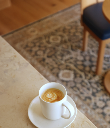 A cup of coffee with latte art on a patterned rug background.