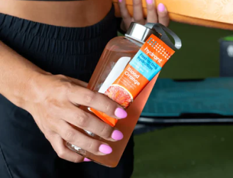 Person holding a blood orange flavored drink bottle.