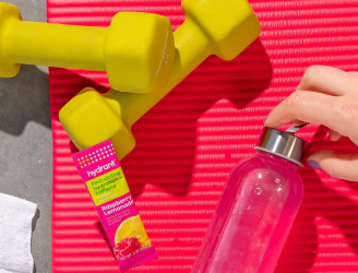 Fitness accessories: Yellow dumbbells, red mat, water bottle, and hydration packet.