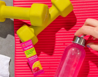 Yellow dumbbells, a red yoga mat, a hand holding a water bottle, and a Hydrant drink mix pouch.