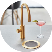 Elegant brass faucet and cocktail glass on a modern countertop.